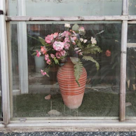 Brightly glazed ceramic vases arranged with fresh wildflowers on a windowsill.