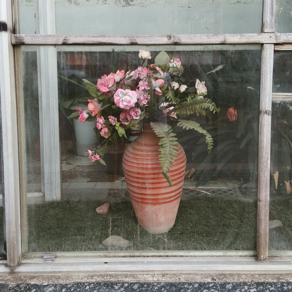 fleurs roses dans un pot en argile brune