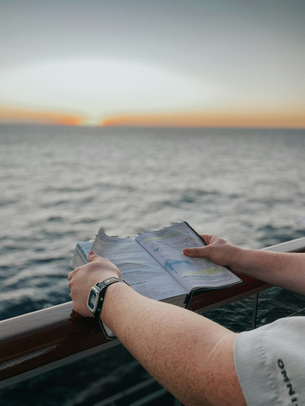 person reading book on brown wooden table