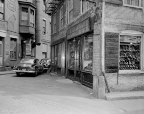 grayscale photo of cars parked beside building