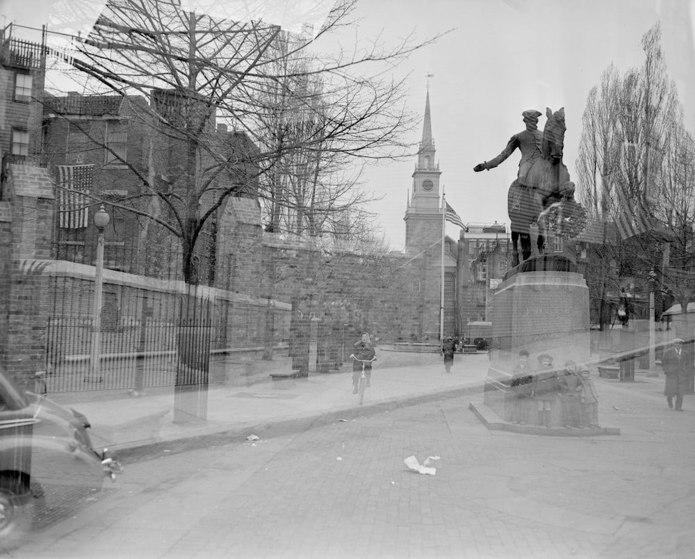 grayscale photo of man riding bicycle on road