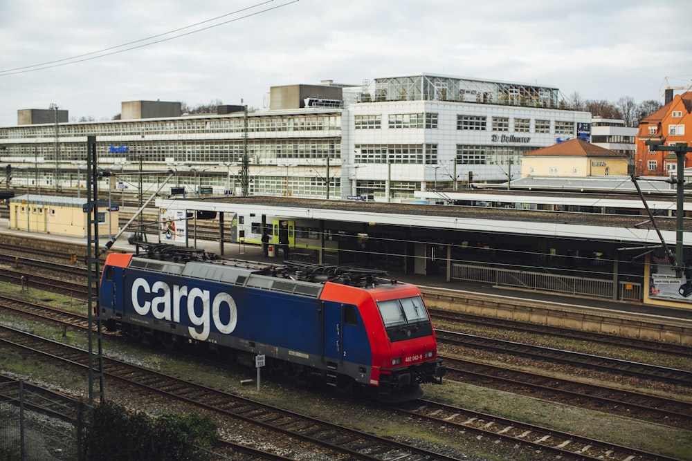 red and blue train on rail tracks during daytime