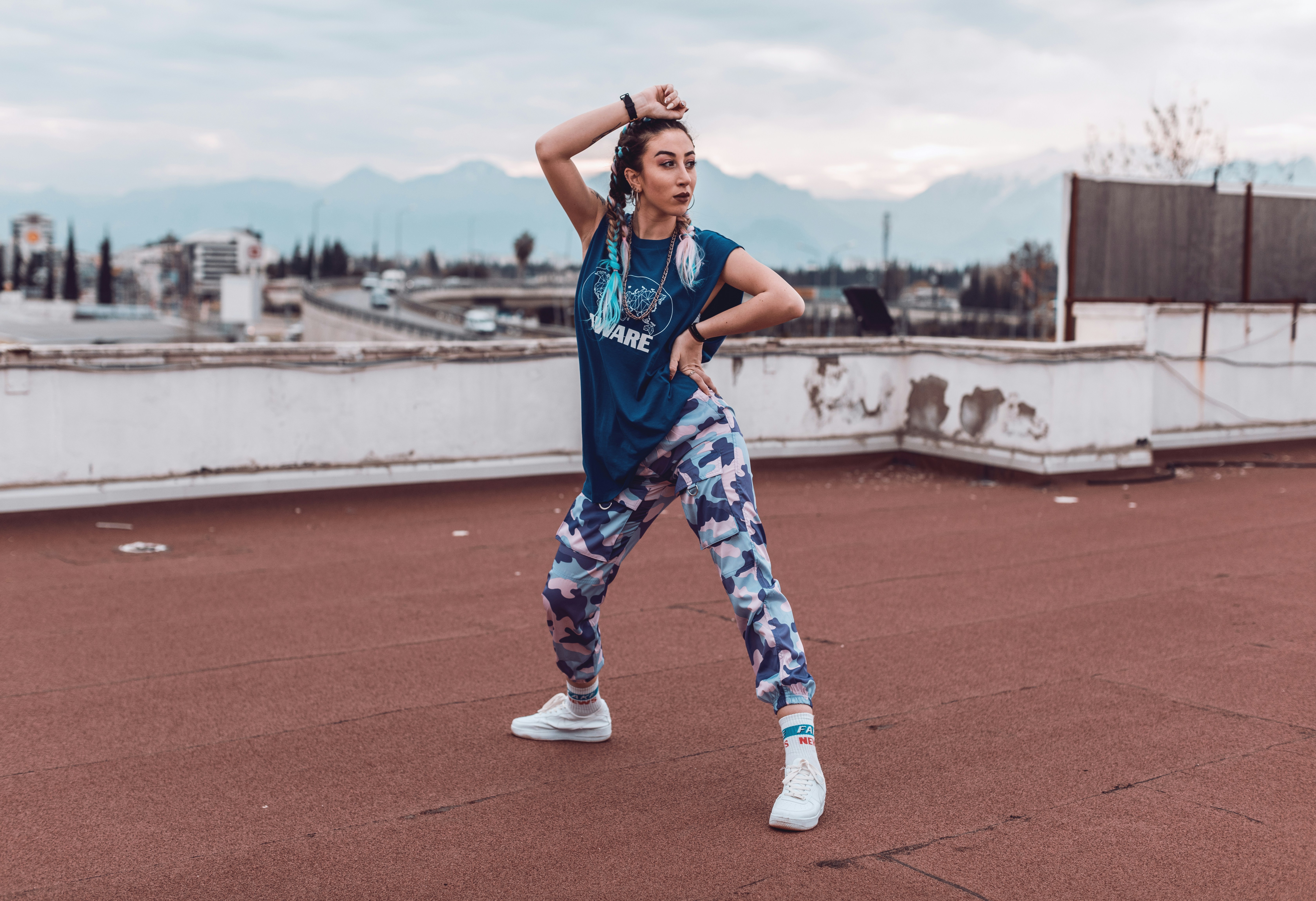 青と白のジャージシャツとズボンの女性が日中に陸上競技で走っている