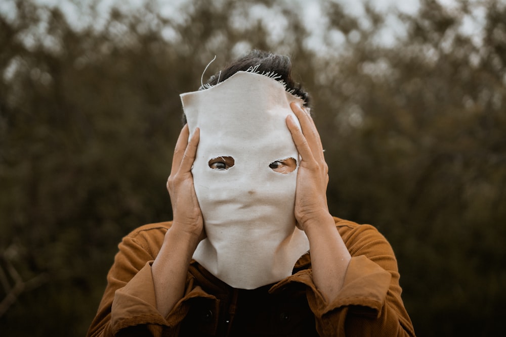 person in brown leather jacket covering face with white face mask