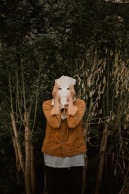 man in brown zip up jacket covering face with white textile in Bandung Indonesia