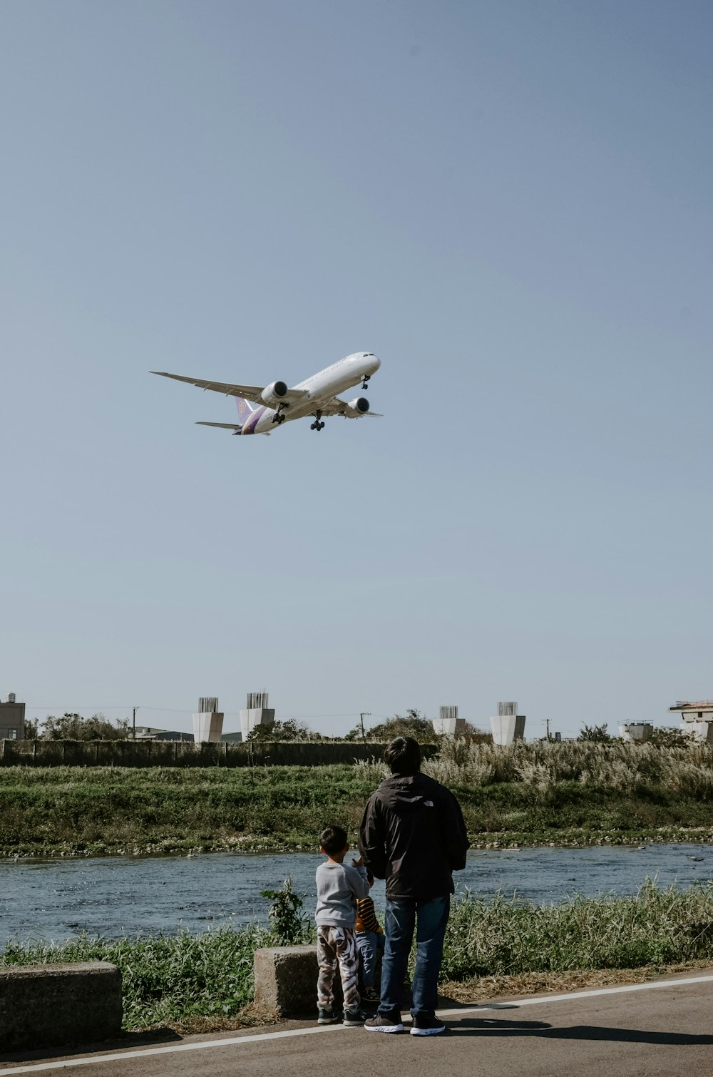 Hombre en chaqueta negra de pie cerca del avión blanco durante el día