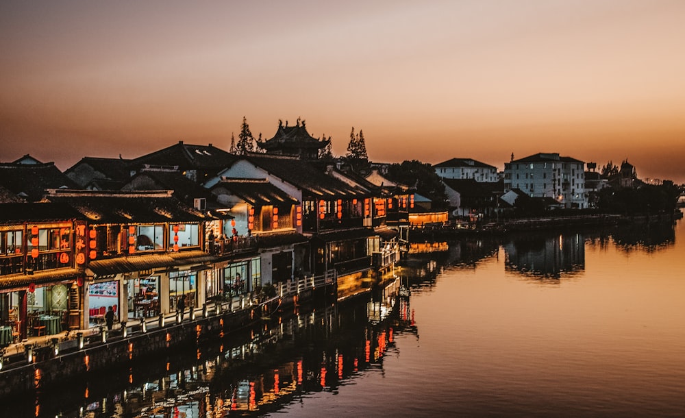 brown and white houses near body of water during sunset