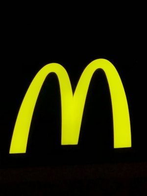 A bright yellow, large and bold 'M' shape against a stark black background, symbolizing a well-known fast-food brand.