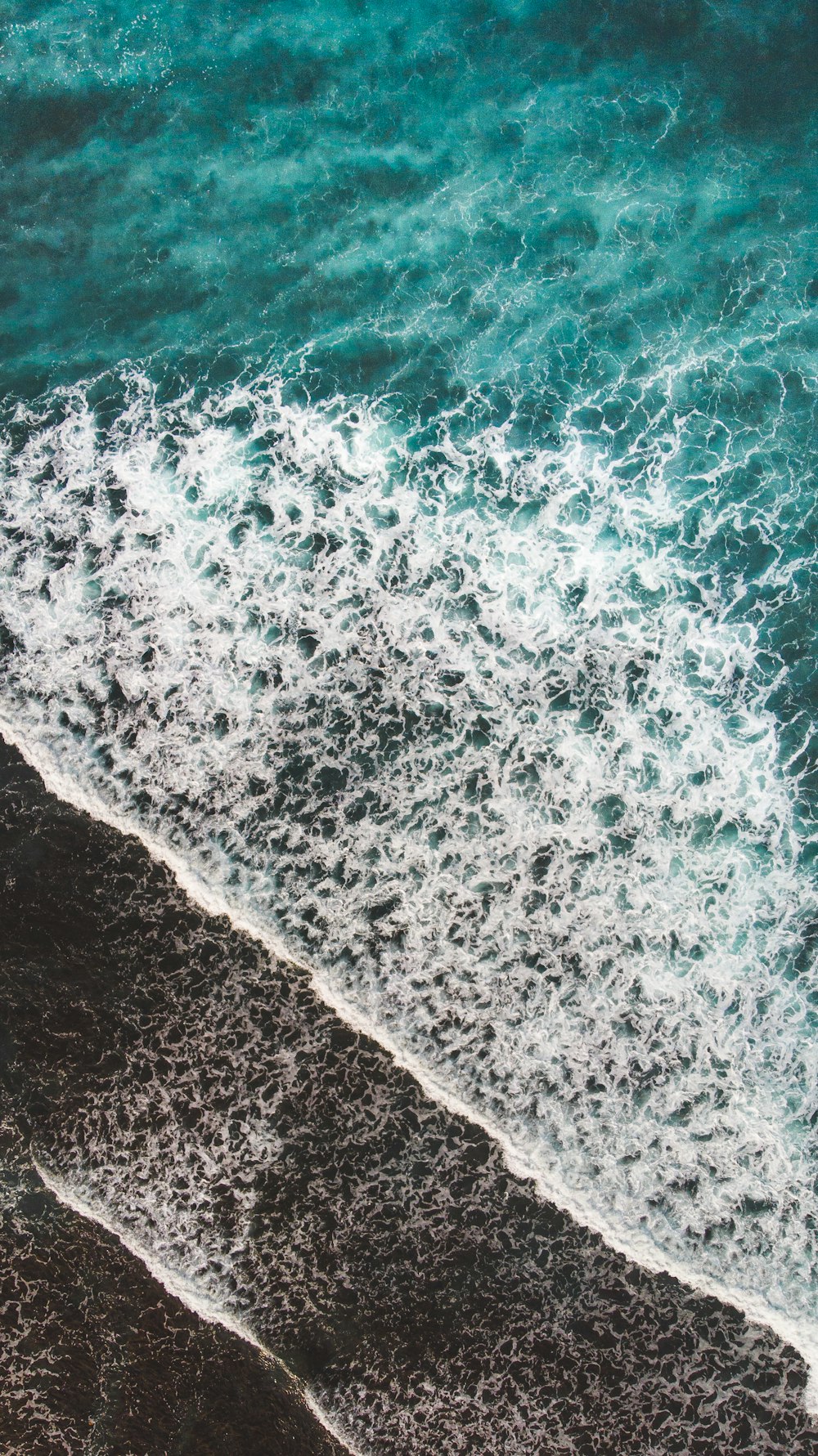 aerial view of ocean waves on shore during daytime