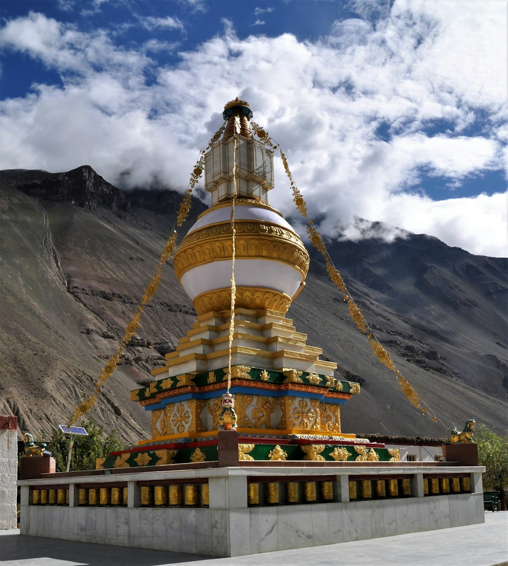 gold and gold tower near mountain under cloudy sky during daytime