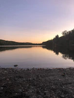 A serene lakeside view with a sunset reflecting on the water.
