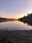 A tranquil lakeside view at sunset with gentle waves and distant hills.