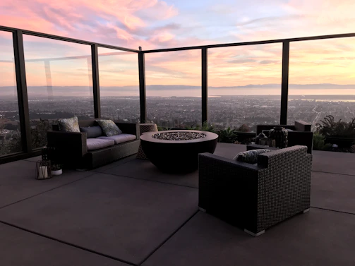 Cozy outdoor seating area beside a modern gray and white home with a warm fireplace and large screen TV.