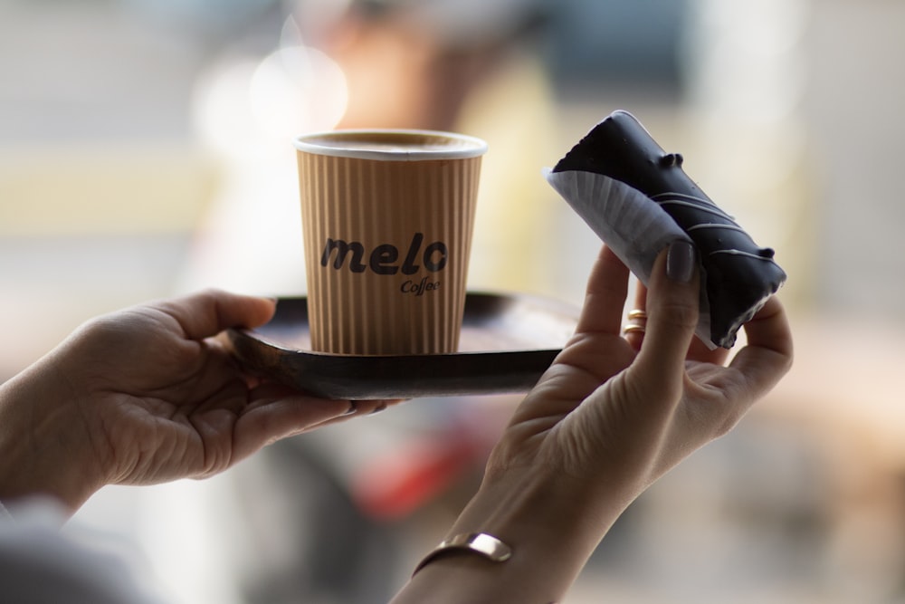 person holding brown paper cup