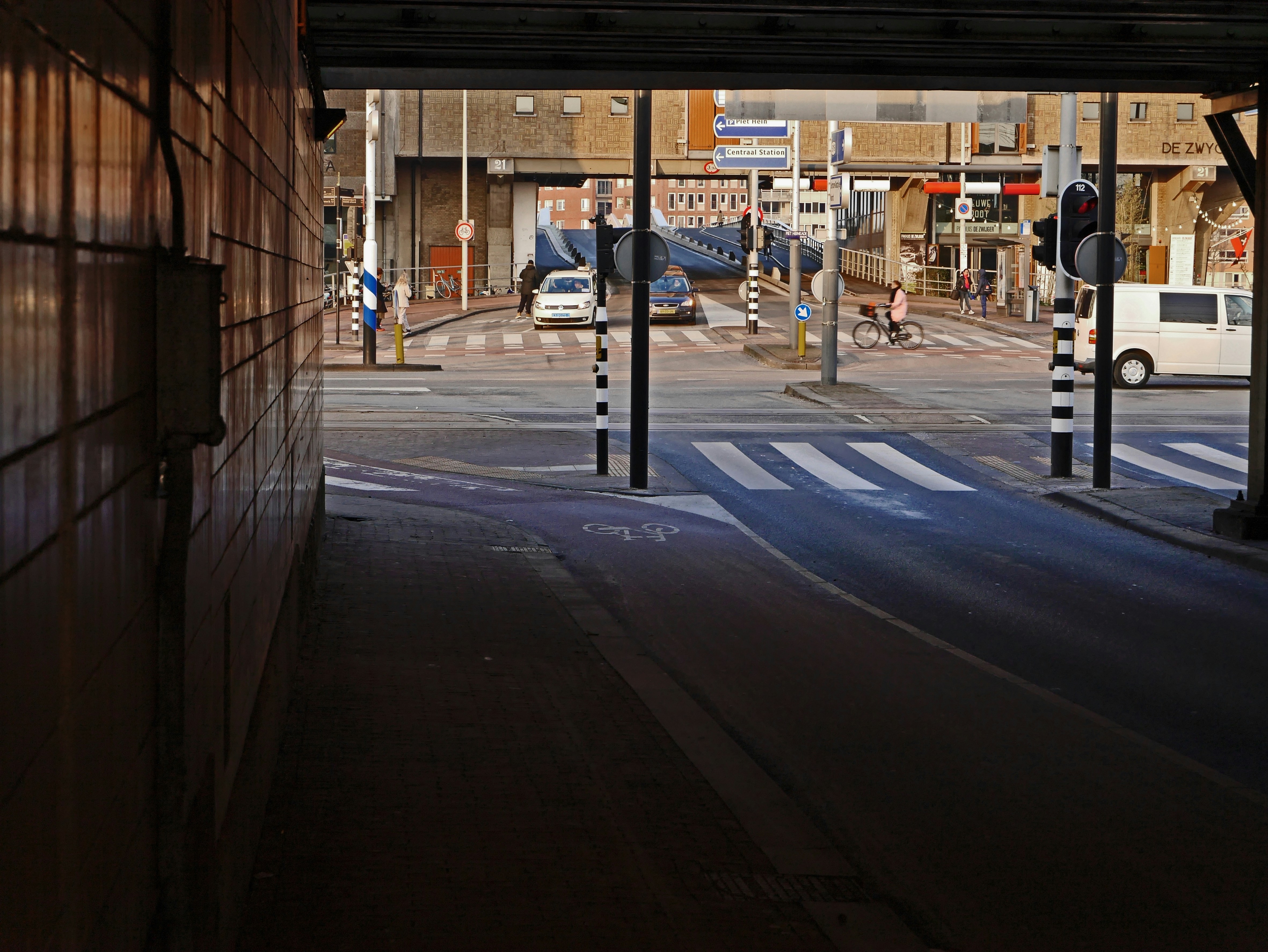 Free photo of Amsterdam city - a look-through view from the dark tunnel to the light at the crossing and the old brickstone ware-house. Under its gate a long bridge follows to Java-eiland. Urban photography of The Netherlands by Fons Heijnsbroek; January 2017. Dutch: Foto Amsterdam - een doorkijk door de tunnel onder het spoor. In het licht voorbij het kruispunt staat het bakstenen pakhuis De Zwijger. Door de onderdoorgang die daaronder werd gemaakt, is nu de Jan Schaeferbrug zichtbaar en bereikbaar, die doorloopt naar Java-eiland. Foto van Amsterdam, januari 2017.
