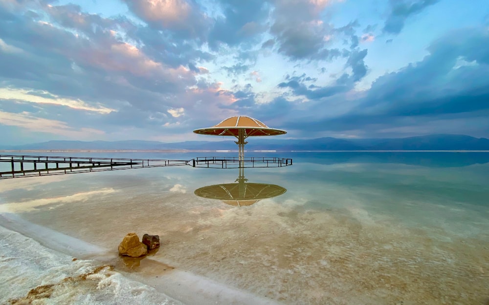 brown wooden beach lounge chair on white sand near sea under blue sky during daytime