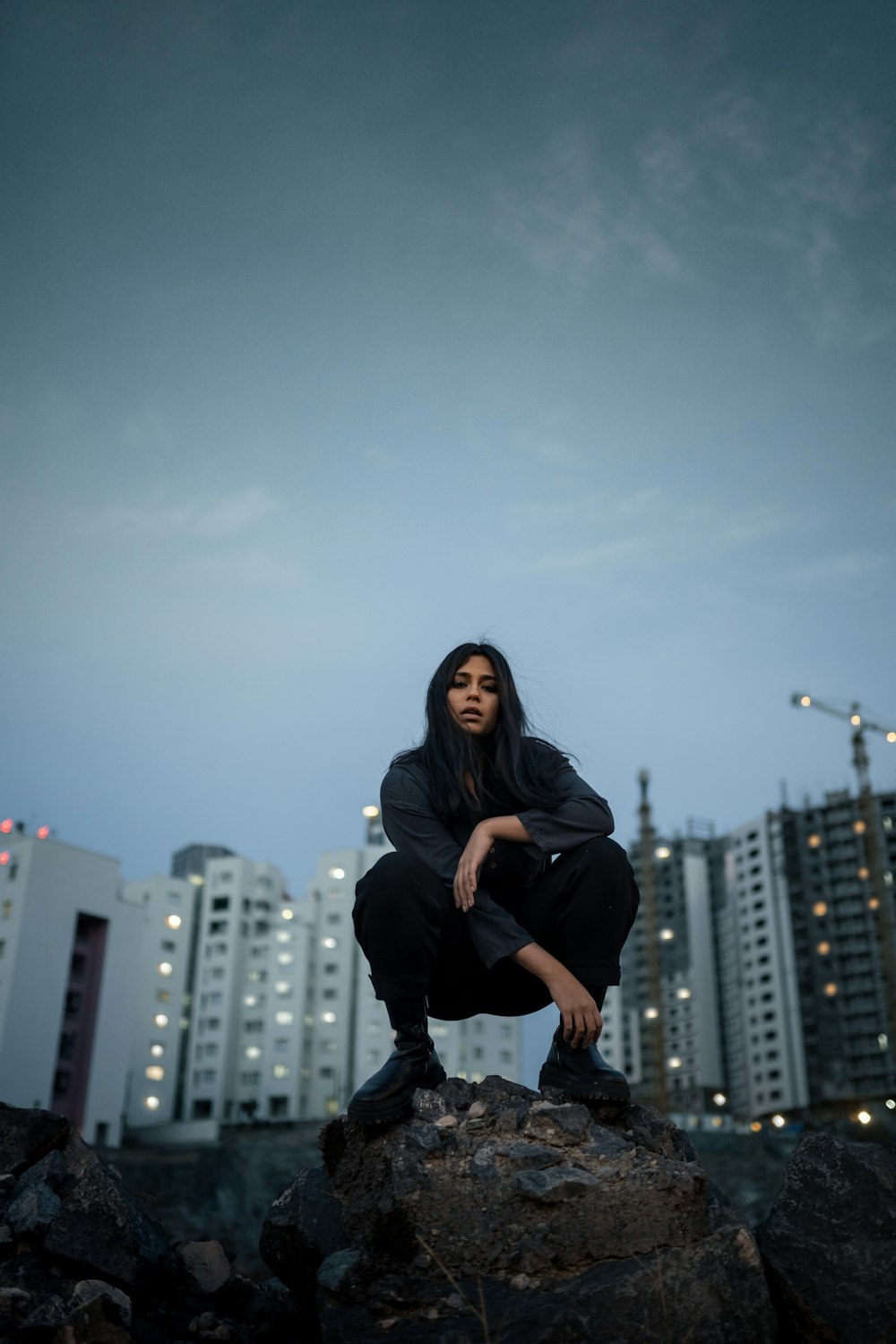 woman in black long sleeve shirt and black pants sitting on black metal railings during daytime