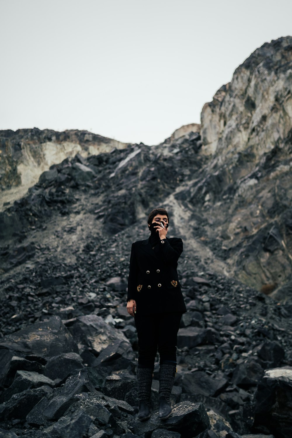 mulher na jaqueta preta de pé na montanha rochosa durante o dia