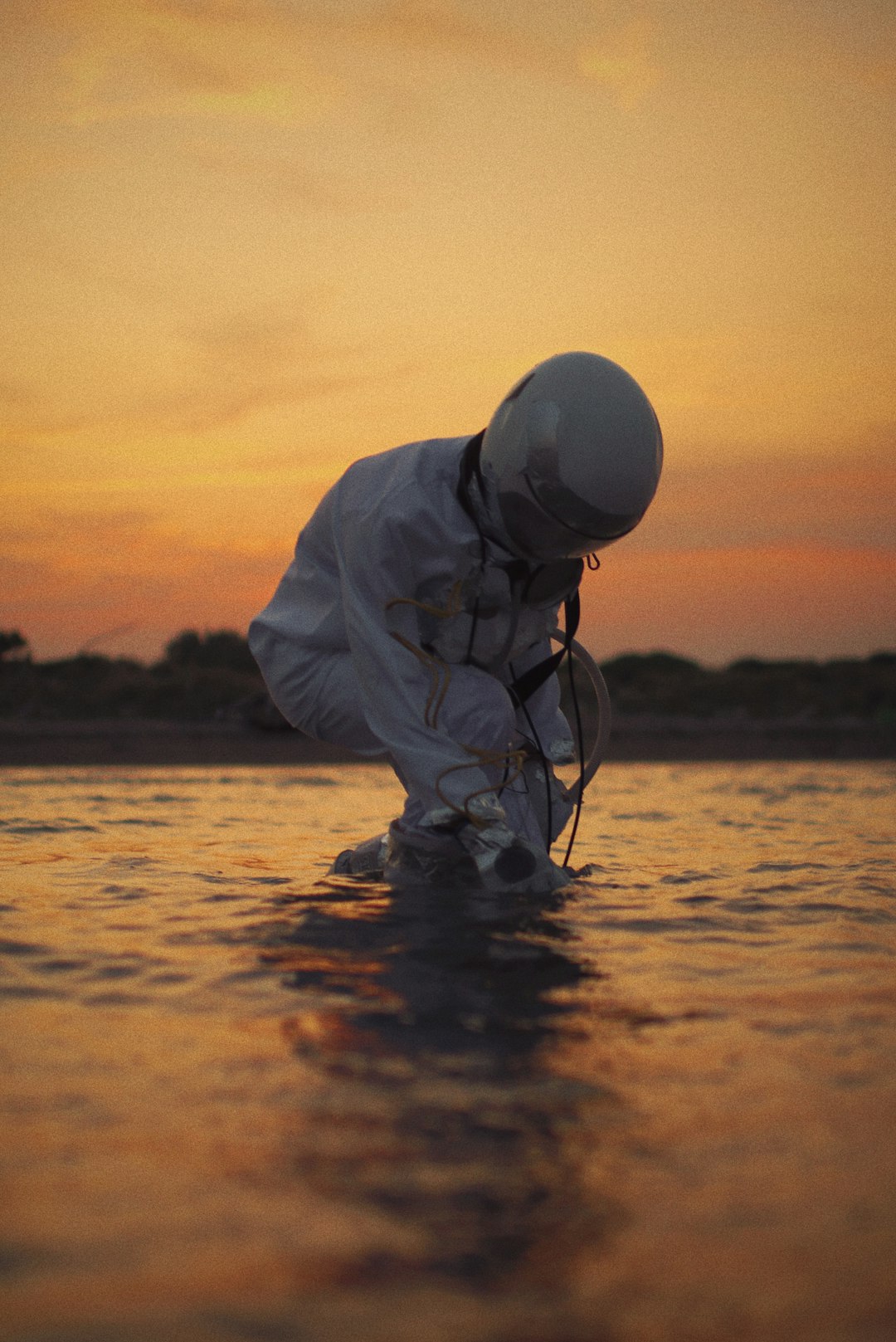 man in white dress shirt and black pants fishing on sea during sunset