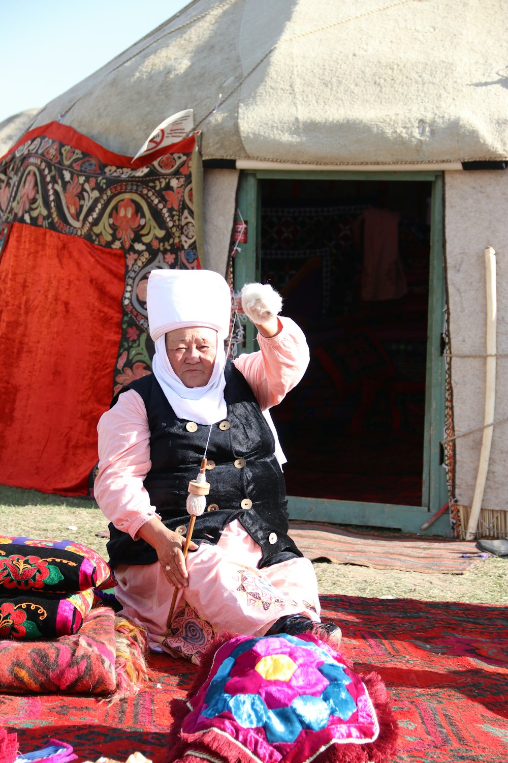 a woman sitting on the ground in front of a tent