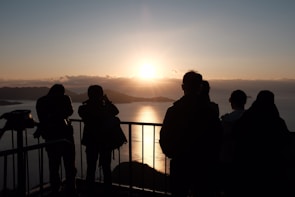 A group of pilgrims walking along a riverbank at sunrise.