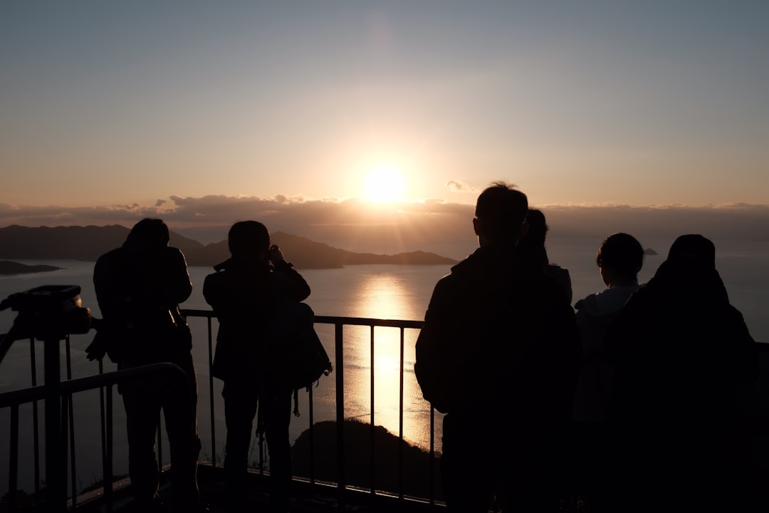 silhouette of people standing on seashore during sunset