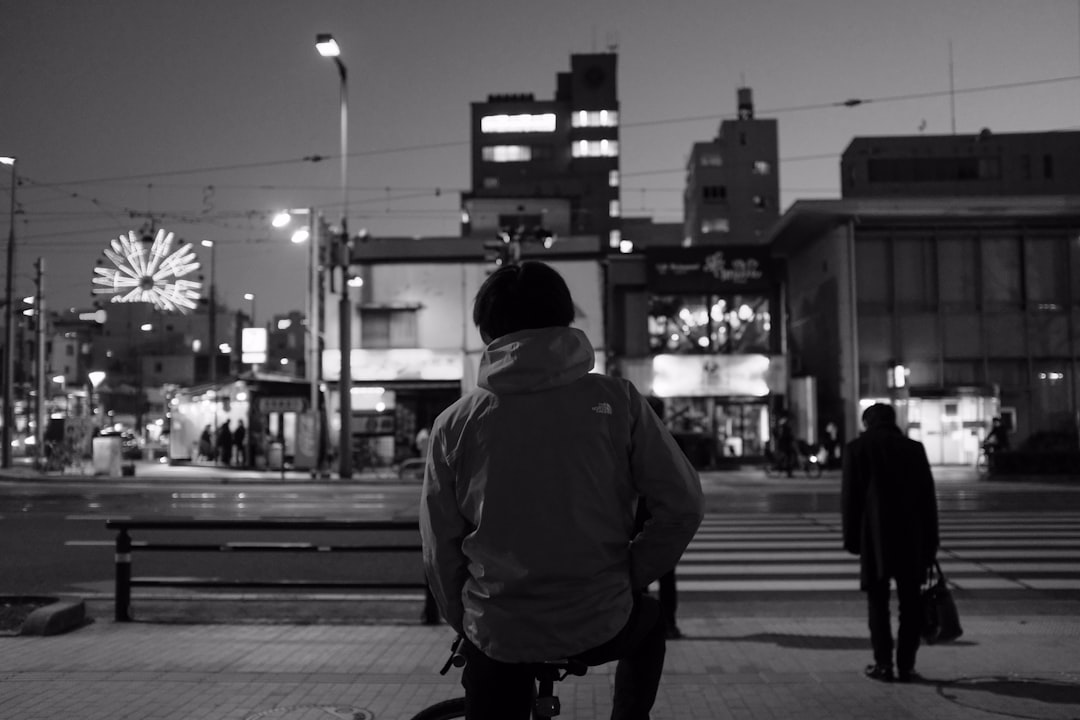 man in hoodie walking on sidewalk during night time