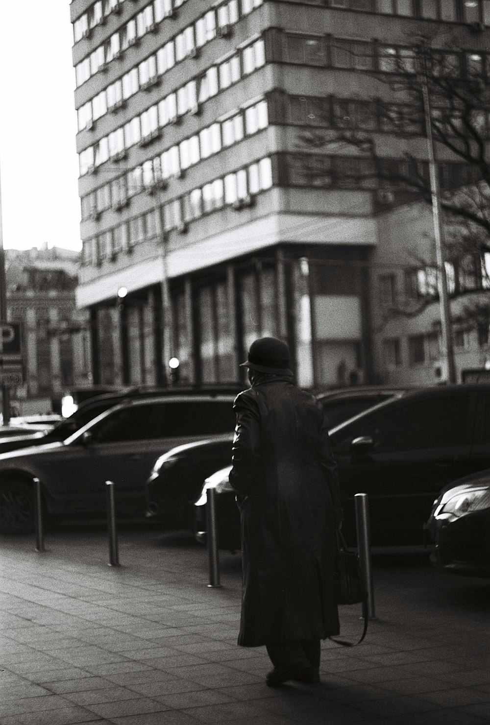 man in black coat standing near cars in grayscale photography