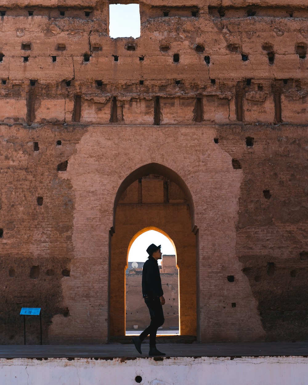 Donna in camicia nera a maniche lunghe in piedi davanti al muro di mattoni marrone