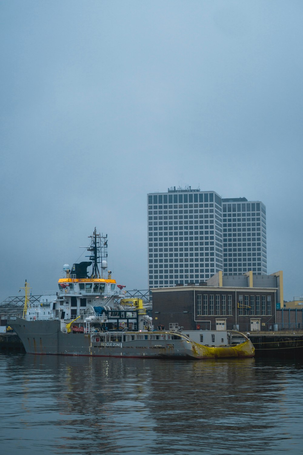 white and yellow ship on dock near city buildings during daytime
