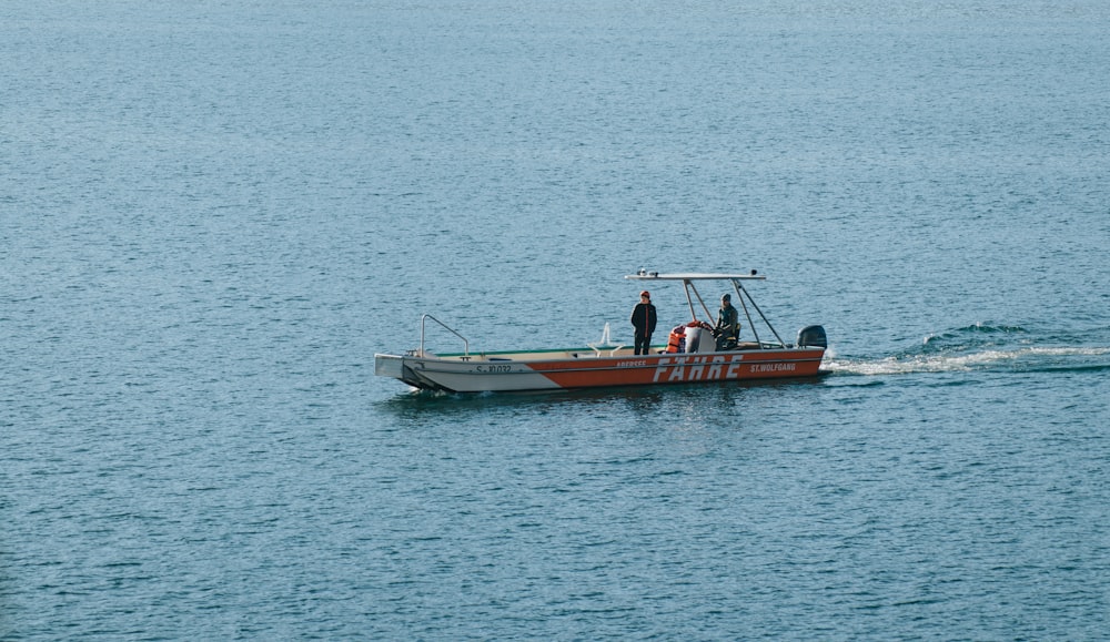 2 men riding on red and white boat on sea during daytime
