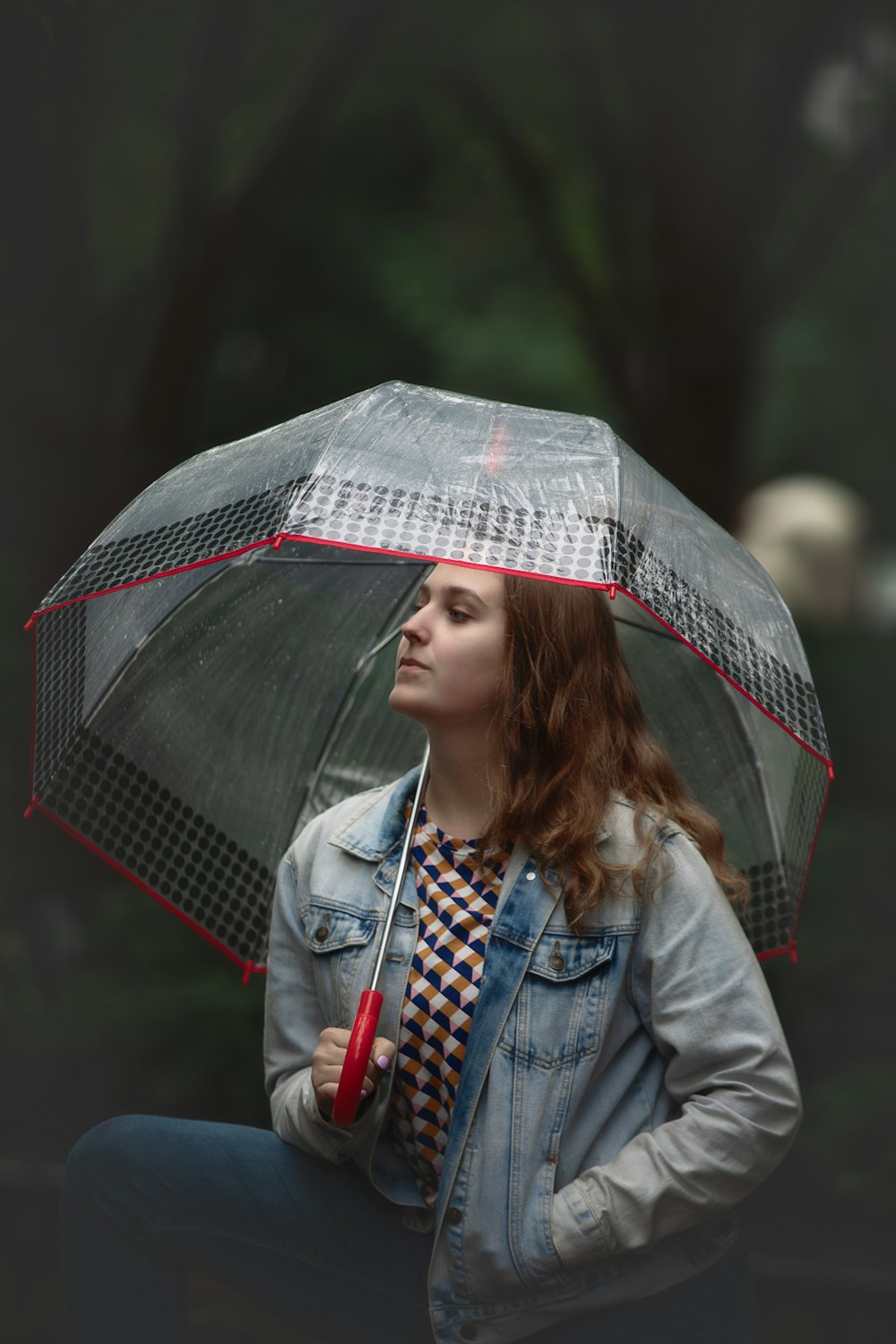 mulher na jaqueta jeans azul que segura o guarda-chuva