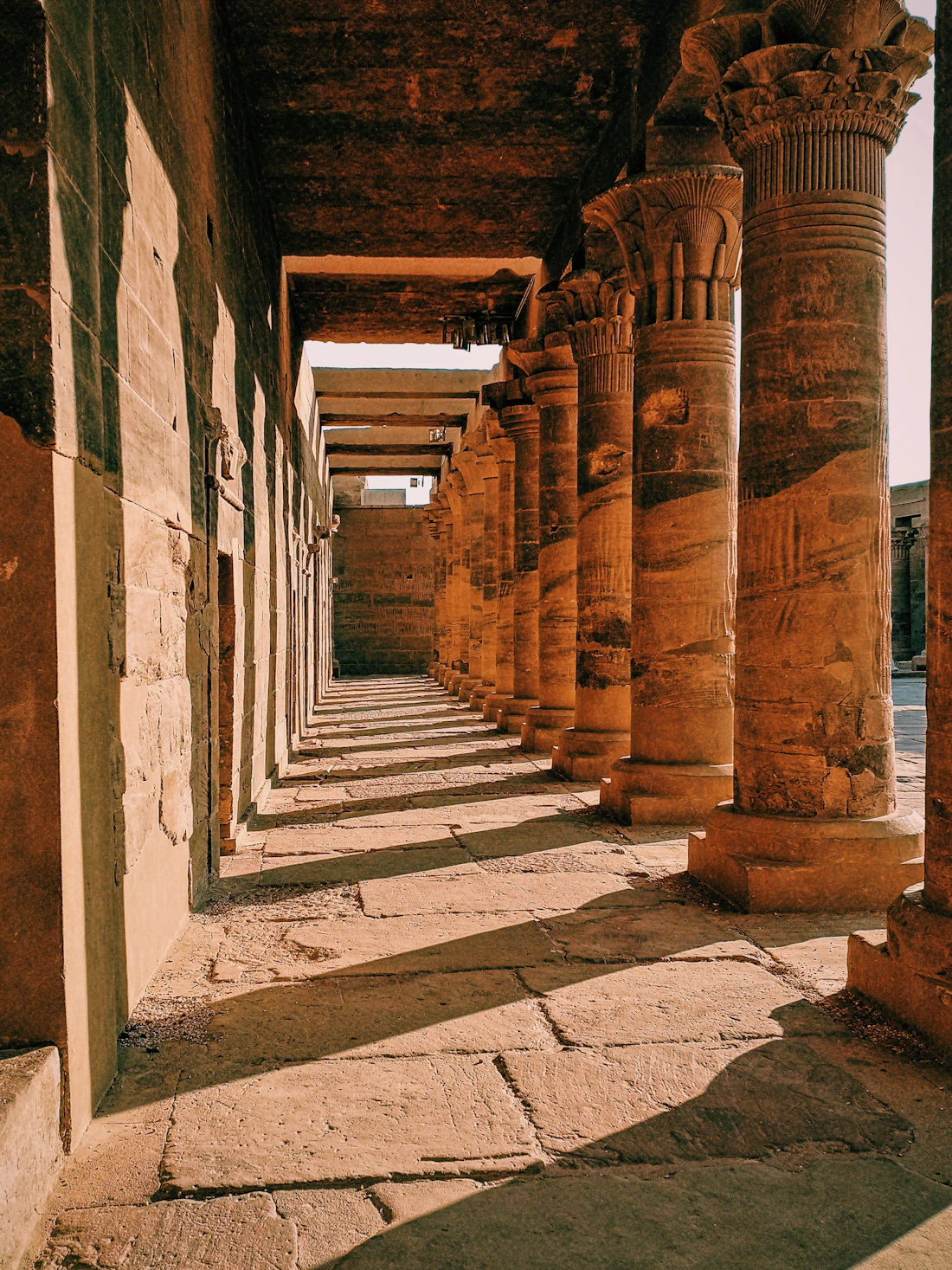Sunlight falling between the ancient carved columns of an Egyptian temple hall