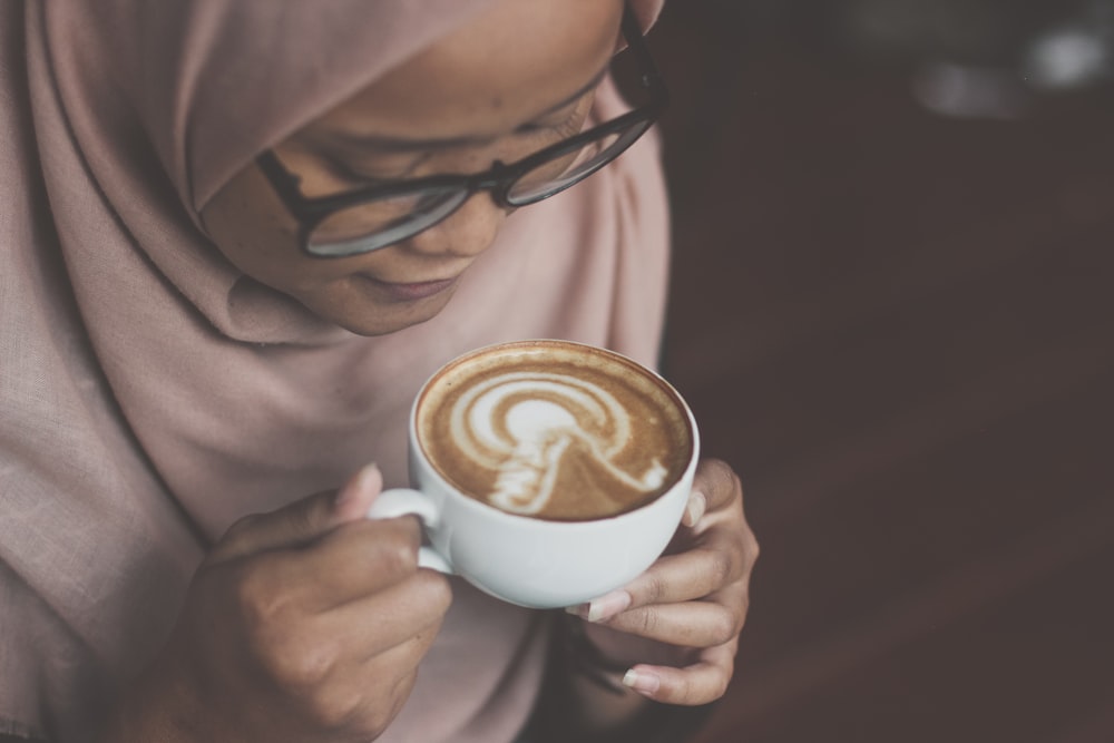 Person mit weißem Keramikbecher mit Kaffee