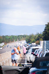 A flat tire being replaced on a busy highway with mountains in the background.