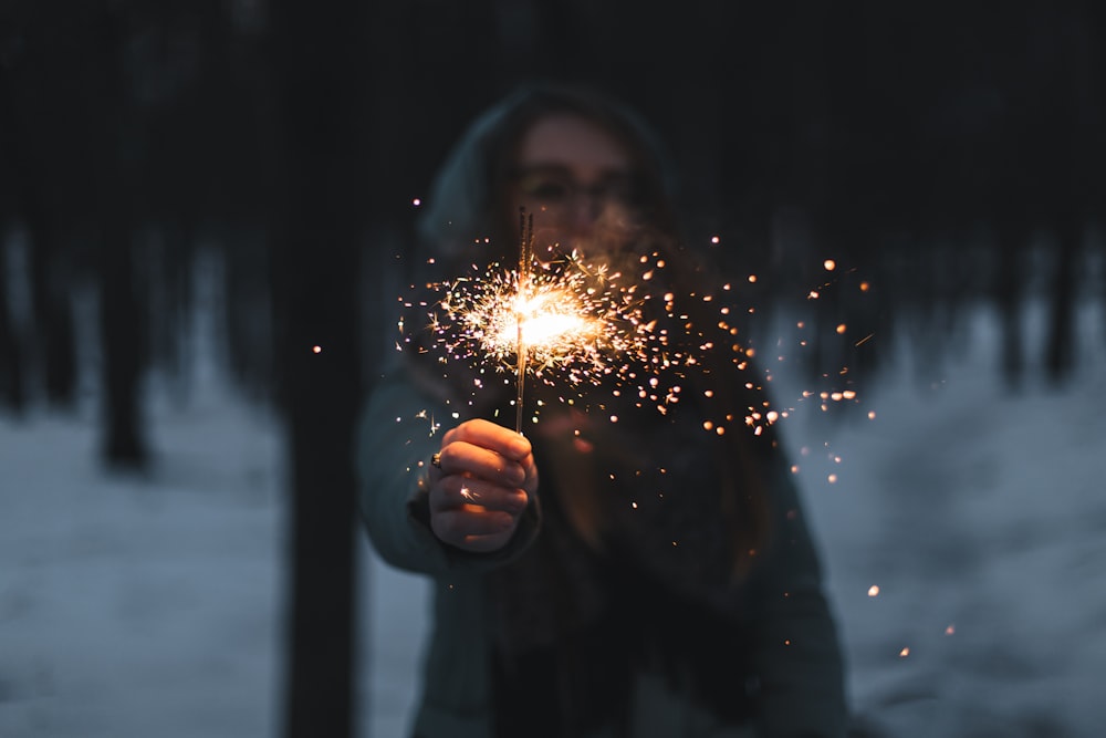 person holding lighted sparkler during night time