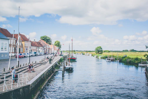 body of water near green trees and houses under white clouds and blue sky during daytime