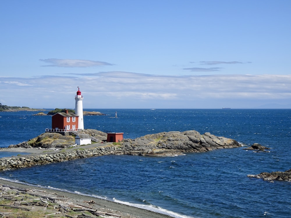 white and red lighthouse on rocky shore during daytime