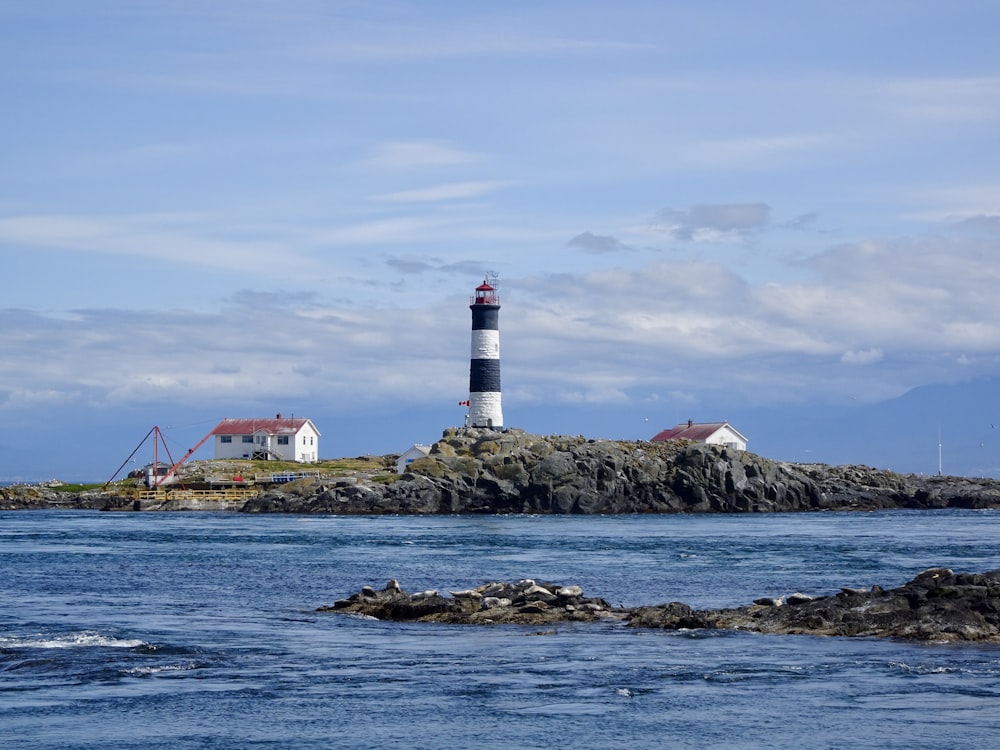 Faro bianco e rosso sulla costa rocciosa durante il giorno