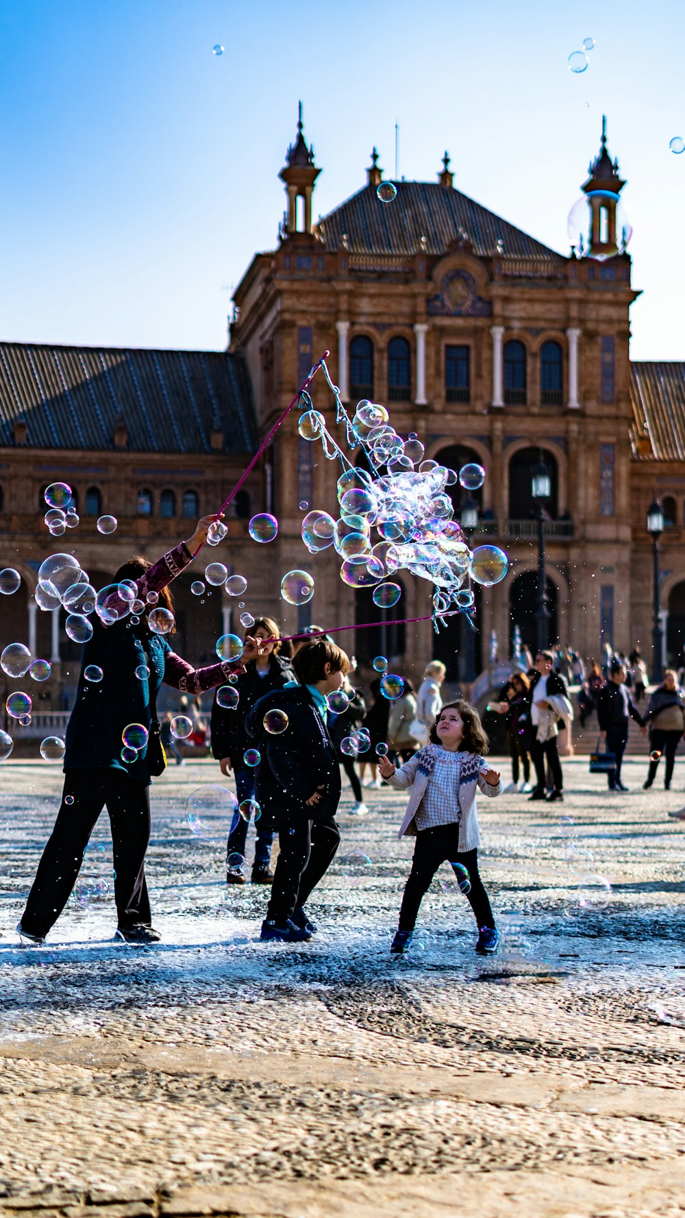 people playing bubbles near brown concrete building during daytime