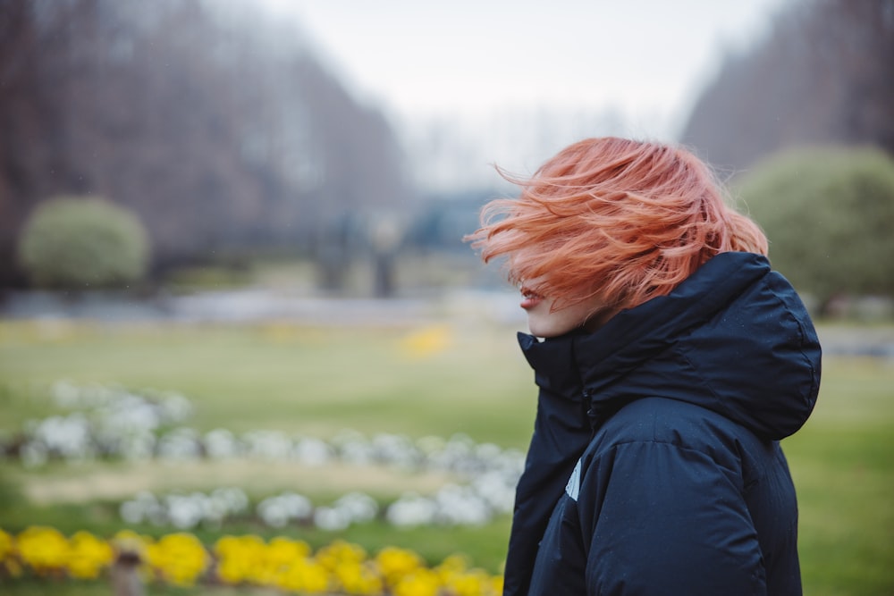 woman in black jacket standing on yellow flower field during daytime