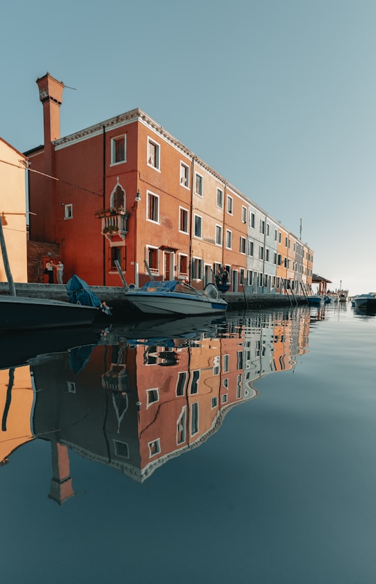 brown concrete building beside river during daytime in Burano Italy