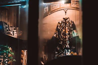 A thobe displayed on a carved wooden mannequin framed by glowing gold and teal lanterns, evoking a regal Moroccan palace ambiance.