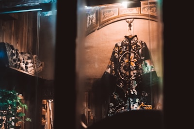 A vibrant, patterned robe hanging on a rustic hook against a textured wall.