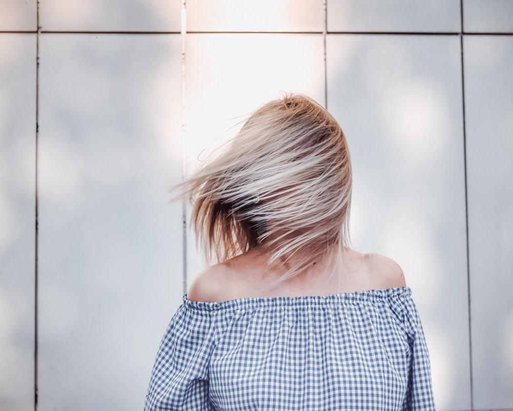 a woman with blonde hair standing in front of a wall