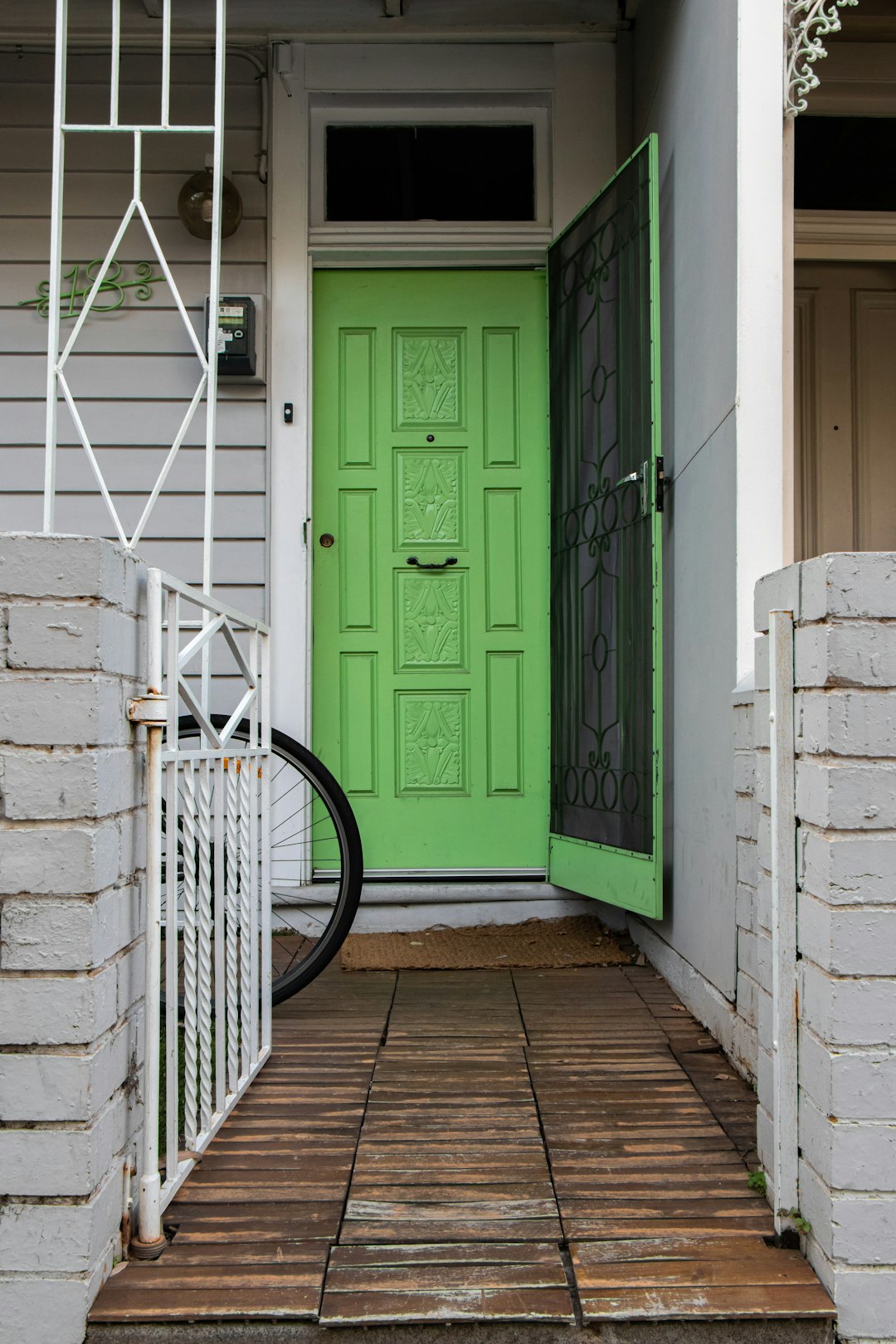 green wooden door beside white concrete wall