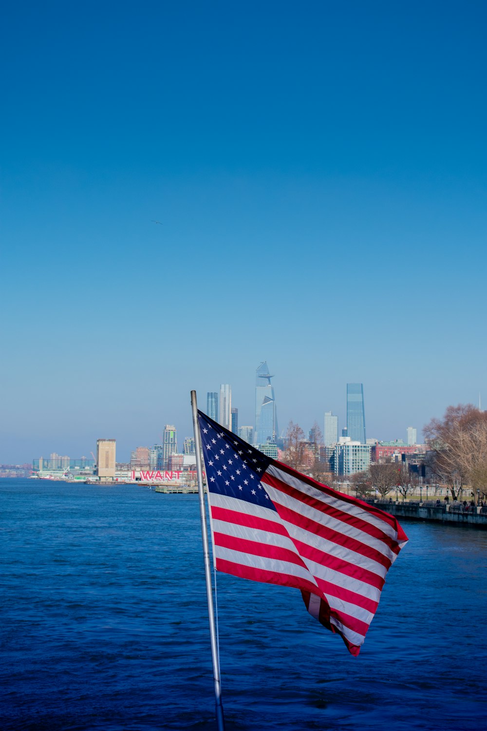 us a flag on pole near body of water during daytime