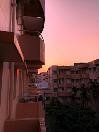 Close-up of a luxury apartment balcony overlooking lush greenery and cityscape at sunset.