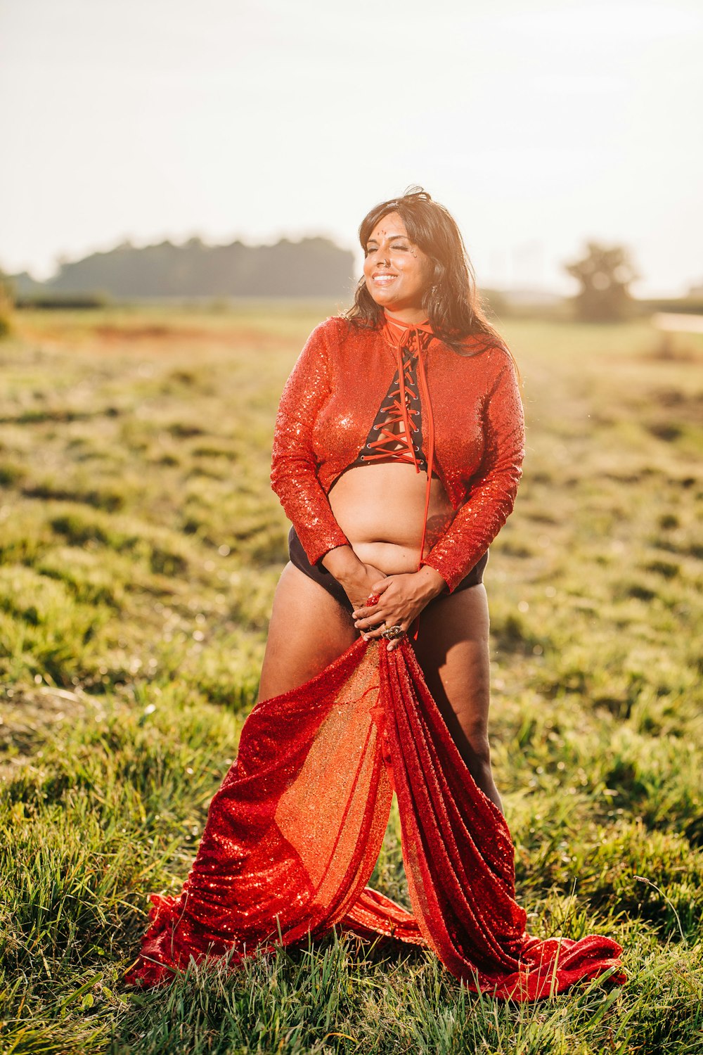 woman in red long sleeve dress standing on green grass field during daytime