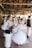 A group of people are engaged in traditional dance, wearing traditional or folkloric clothing. The setting is a rustic wooden building with large windows, and the movement of the dancers creates a dynamic and blurred effect.